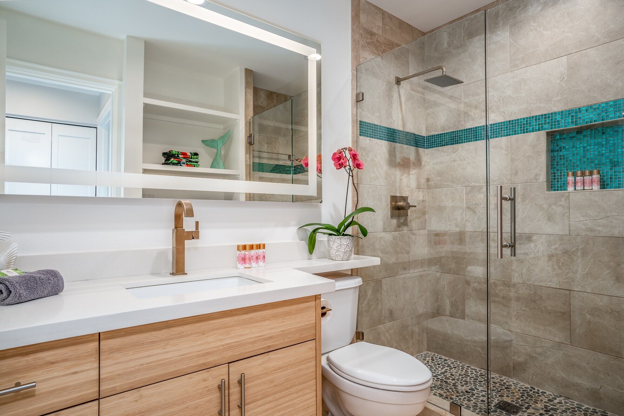 A modern bathroom with a white vanity, a glass shower enclosure, and a decorative mirror.