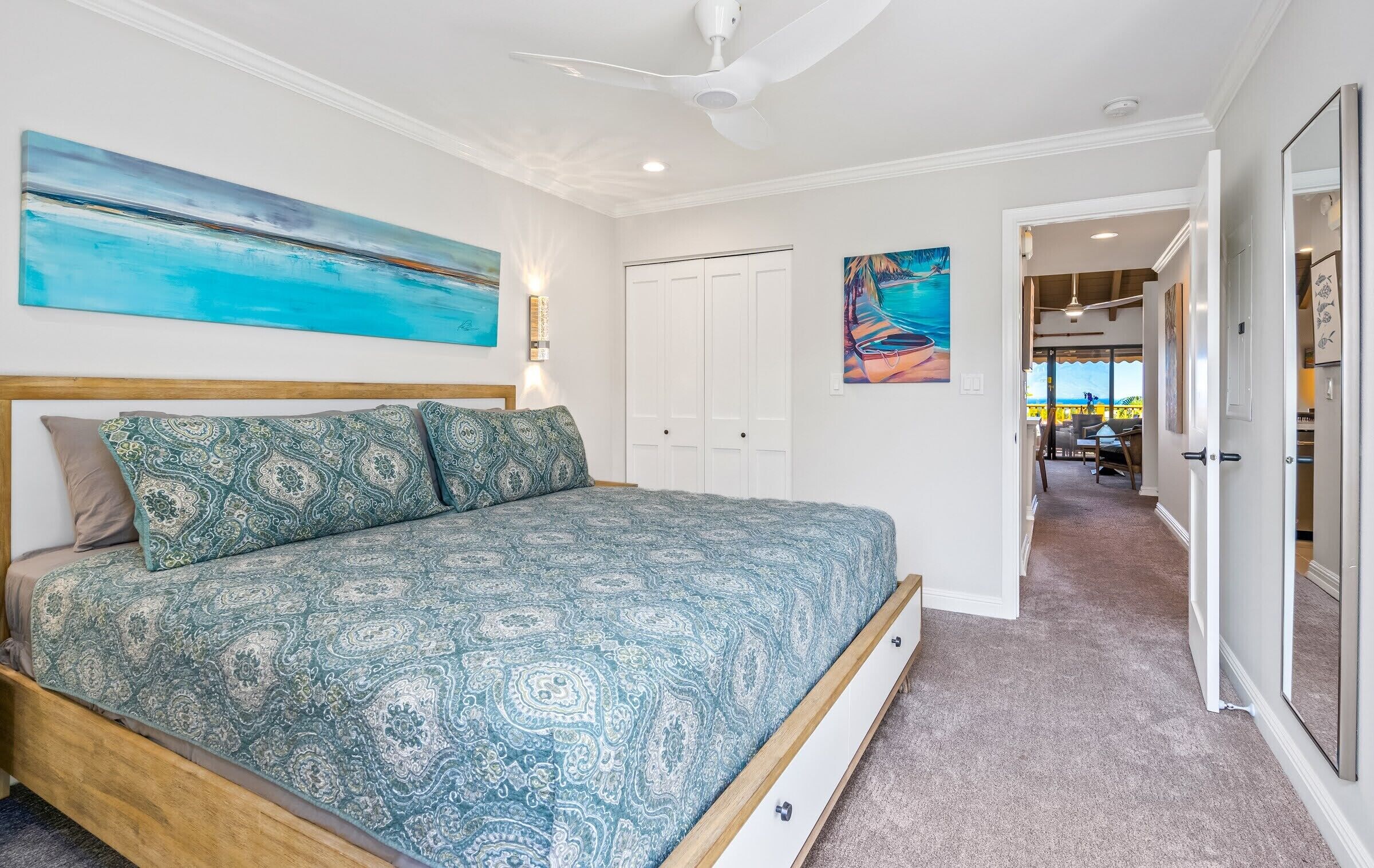 A bedroom with a bed, a ceiling fan, and a door leading to another room.