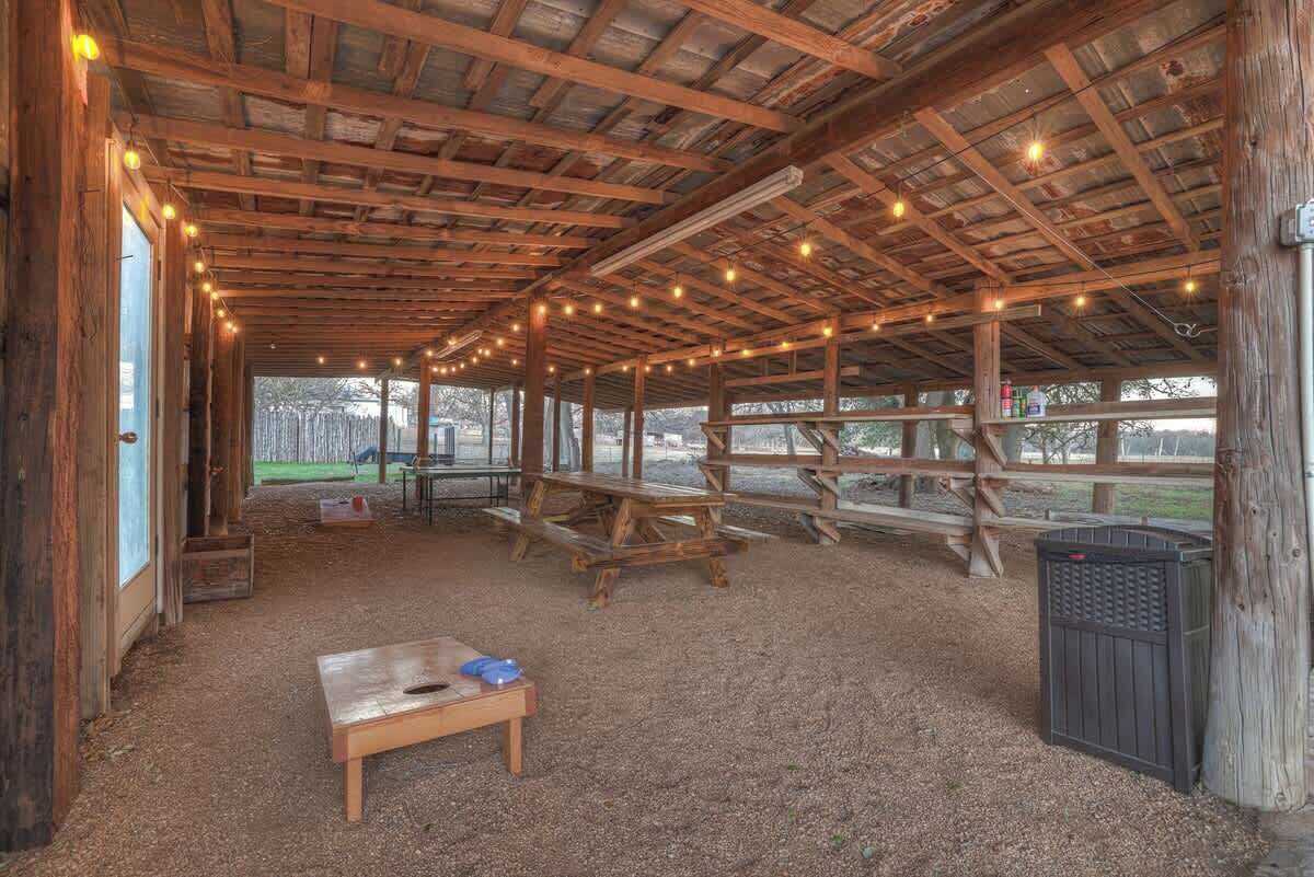 An indoor wooden structure with a high ceiling, string lights, and a table.