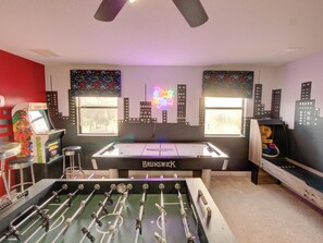 Uma mesa de futebol de mesa em um ambiente com murais de paisagem urbana, um letreiro neon e uma máquina de futebol de mesa.