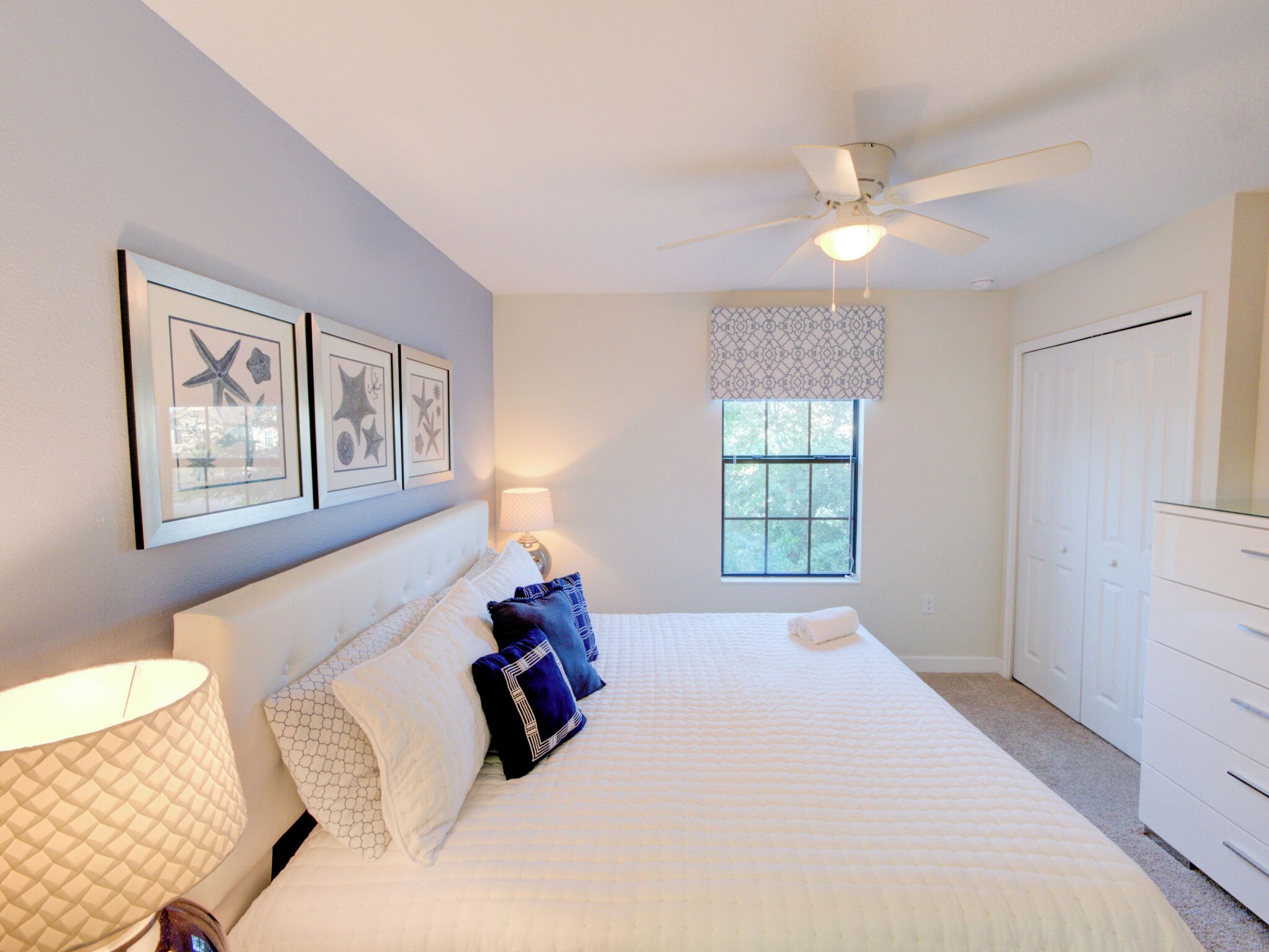 A bedroom with a bed, a ceiling fan, a window, and a door.