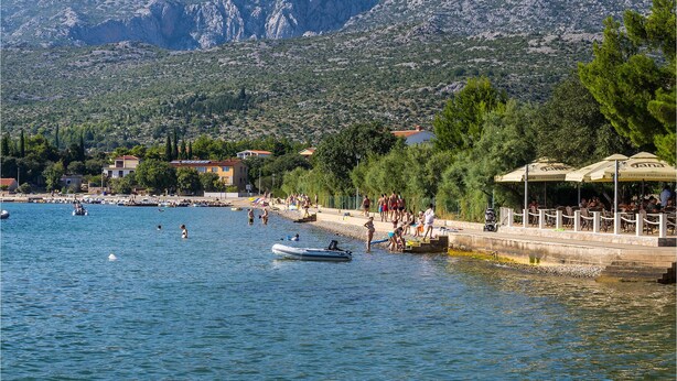 Une zone côtière avec une jetée, des gens qui se baignent et des bateaux.