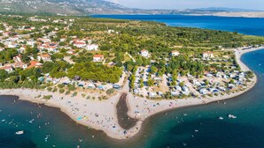 Vue aérienne d’une zone côtière comprenant une plage, un espace de stationnement pour les véhicules de loisirs et un quartier résidentiel avec des maisons.