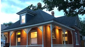 A two-story house with a porch, brick exterior, and a chimney. - Casa de Los Artistas (Albuquerque)