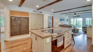 Een ruime keuken met een centraal eiland, houten kastjes en een plattelandsstijl plafond.