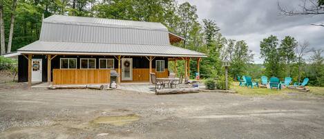A rustic cabin with a porch, a table, and chairs outside.