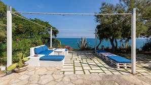 An outdoor seating area with white furniture and blue cushions, overlooking a body of water. - Pet friendly home in Trani with WiFi (Trani)