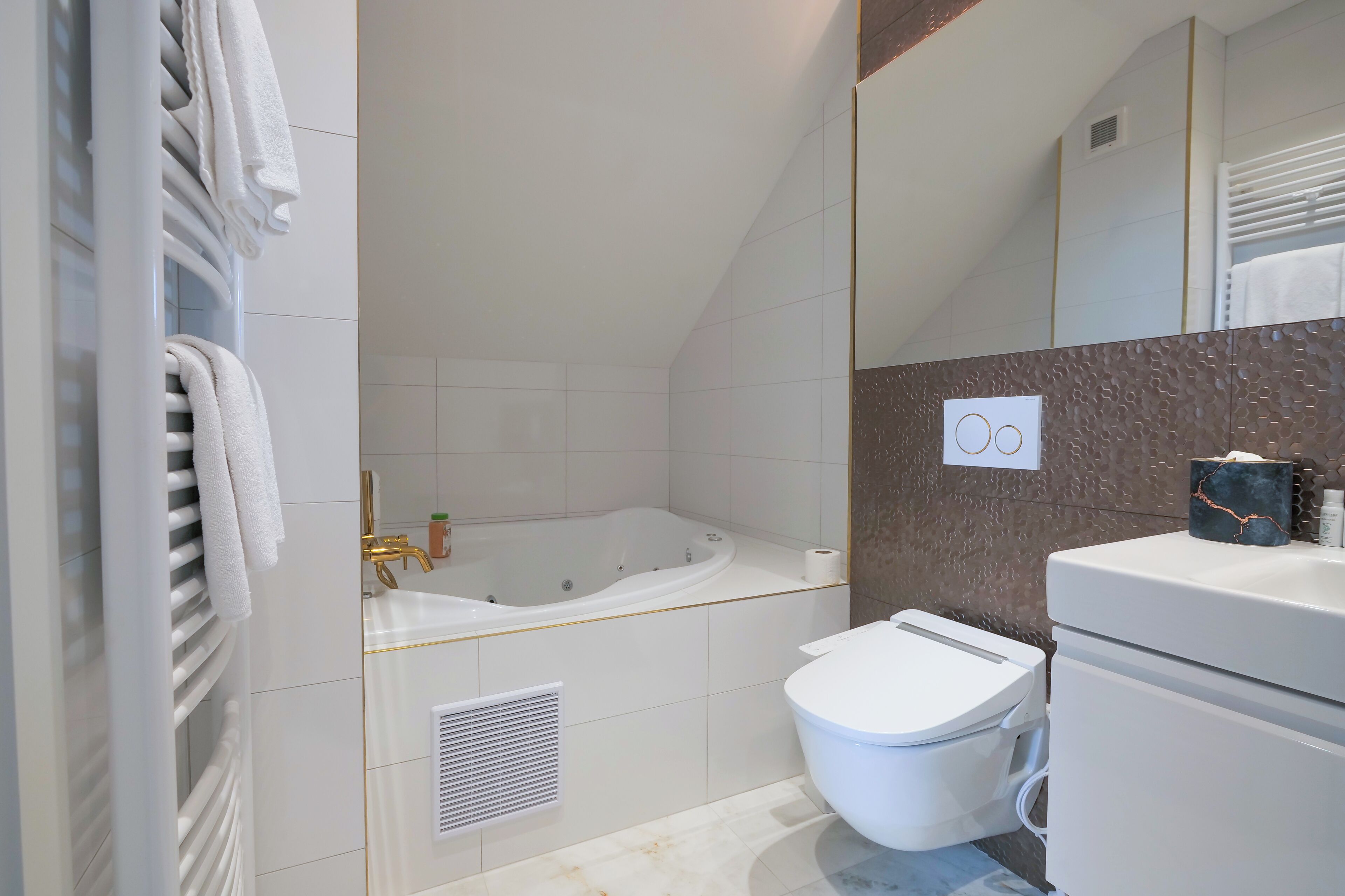 A modern bathroom with a bathtub, toilet, and a large mirror.