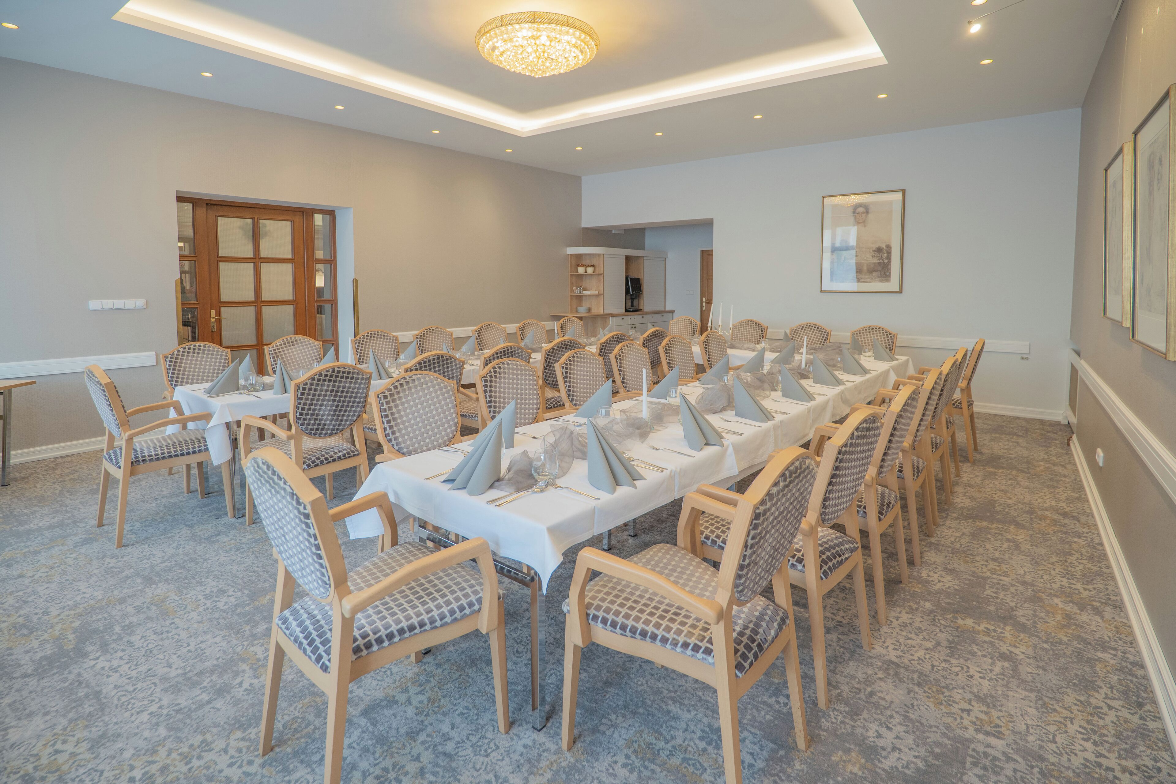 Un salón de conferencias con una larga mesa, varias sillas y una araña.