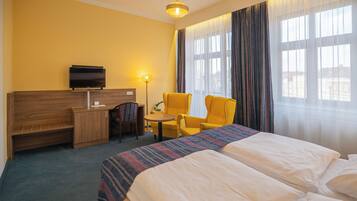 A hotel room with two beds, a desk with a TV, a chair, and a lamp.
