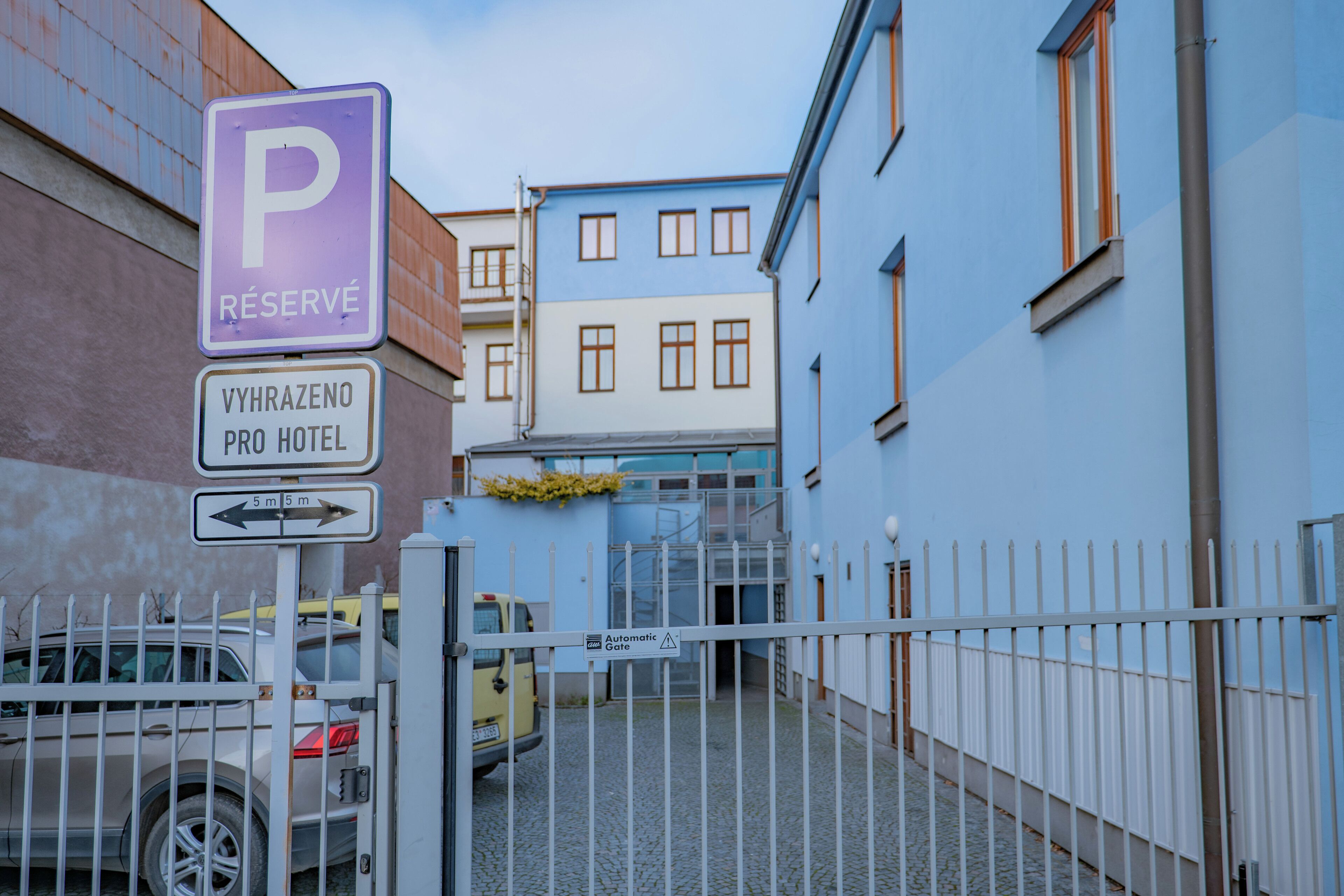 Ein Hotel Eingang mit einem Schild für reservierte Parkplätze, einem Wegweiser für Hotelgäste und einem befestigten Einfahrtsbereich.