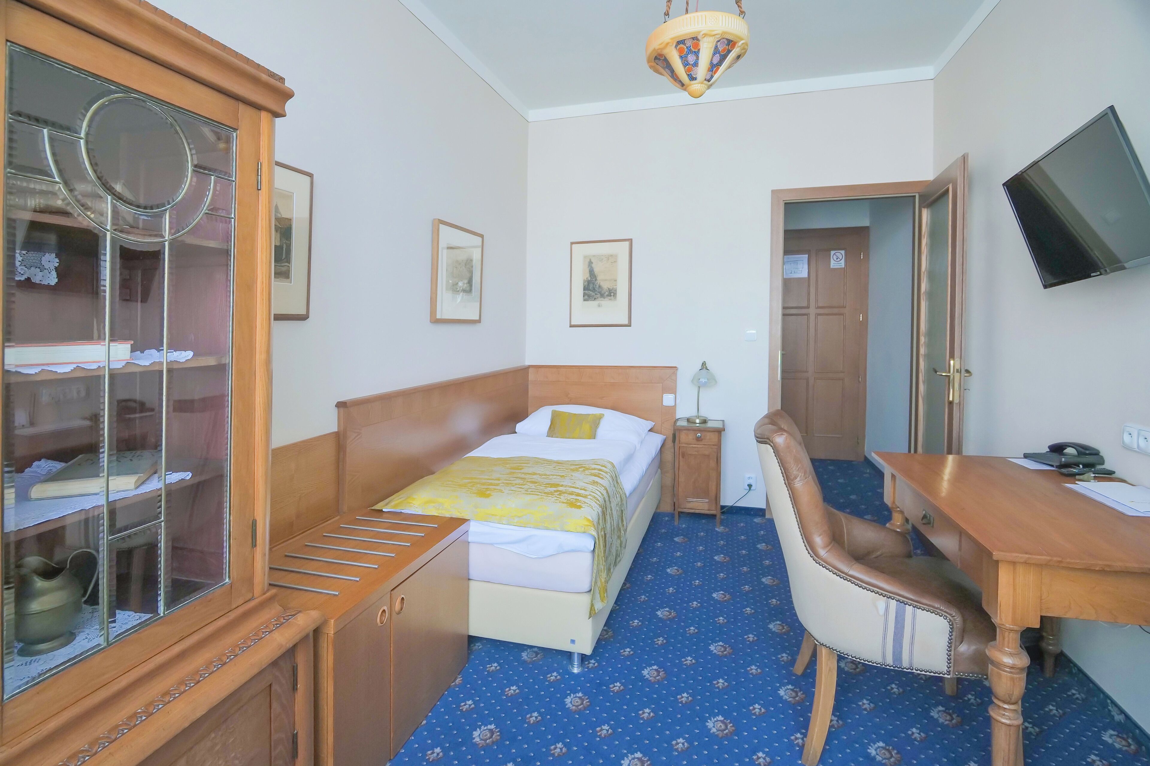 Une chambre d’hôtel équipée d’un lit, d’un bureau, d’une chaise, d’une télévision et d’une armoire.