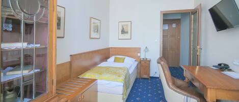 Une chambre d’hôtel équipée d’un lit, d’un bureau, d’une chaise, d’une télévision et d’une armoire.