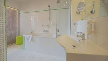 Un baño moderno con bañera, un lavamanos grande y una cabina de ducha de cristal.