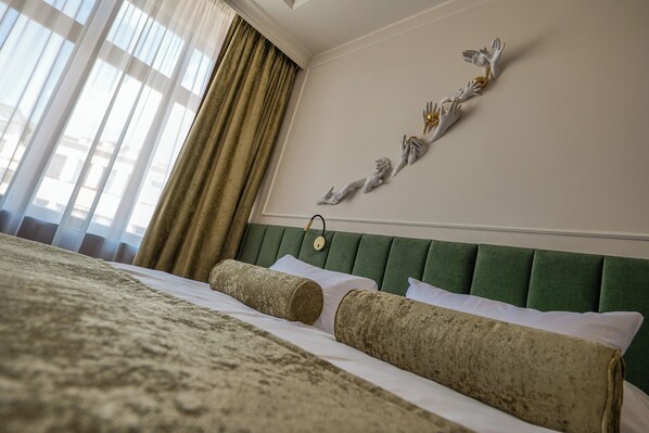 A hotel room with a large bed, green upholstered headboard, and a decorative wall piece. - Hotel Zlatá Hvězda (Litomysl)