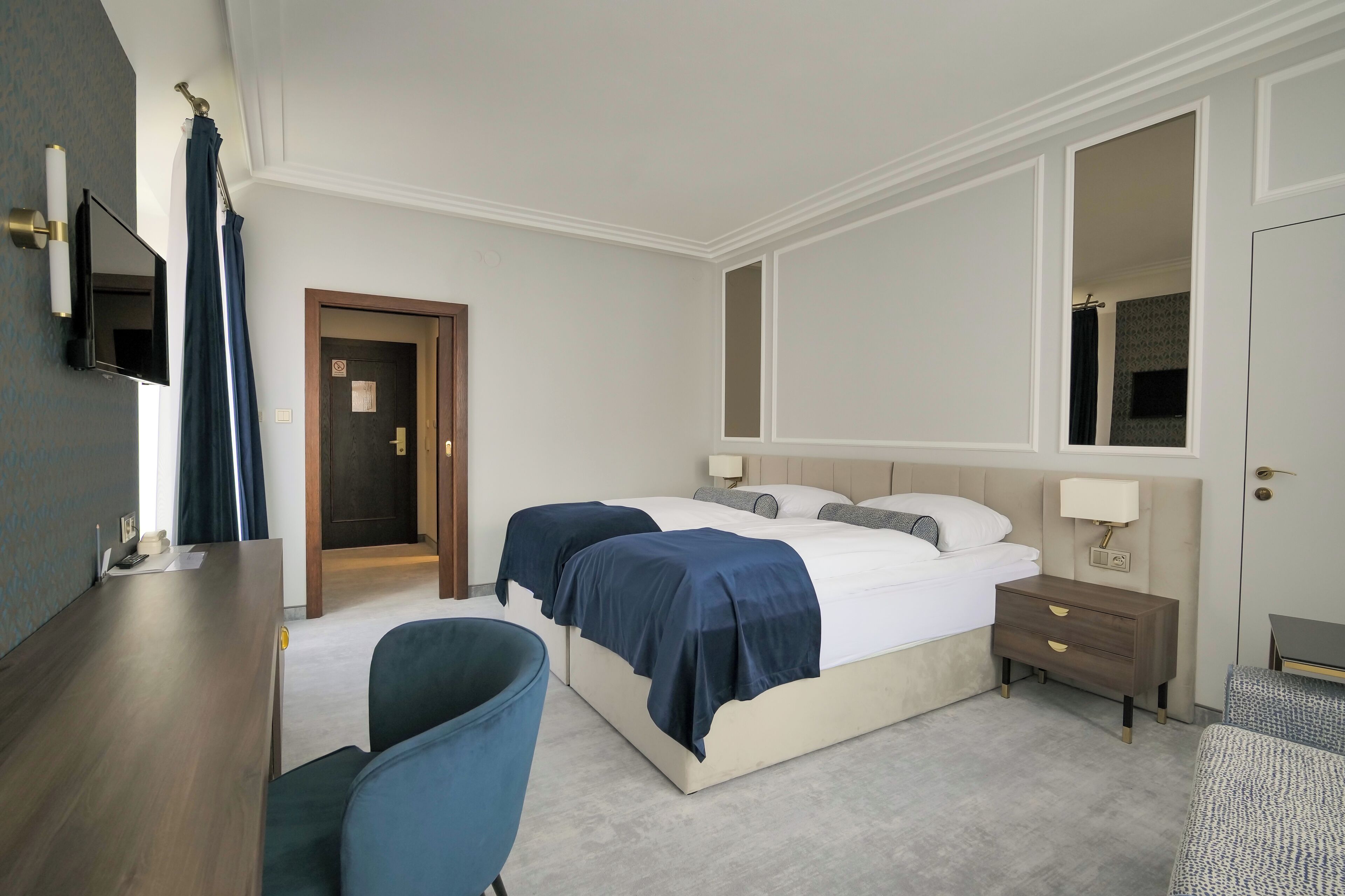 Een hotelkamer met een groot bed, nachtkastjes, een bureau, een stoel en een televisie.