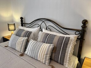 Cozy retreat with a classic headboard, plush pillows, and a bedside lamp.