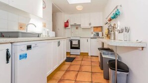 Een compacte keuken met witte kasten, een magnetron, een spoelbak en een klein raam boven het fornuis.