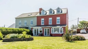 Een twee verdiepingen tellend huis met een rood en grijs gevel, een voortuin en een verzorgd gazon.