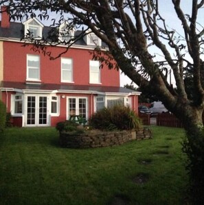 A two-story house with a red exterior, white windows, and a covered porch. - 2 Marconi House, Apartment (Crookhaven)