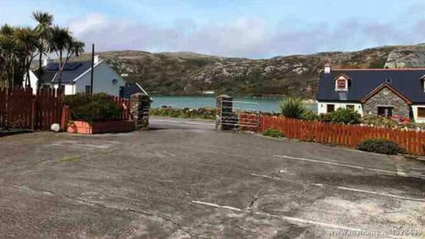 A coastal road leading to a residential area with houses and a body of water in the background. - 3 Marconi House, Apartment (Crookhaven)