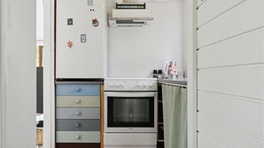 A compact kitchen with a white stove, a small oven, and a countertop with a kettle and salt and pepper shakers. - Stunning home in Askø with kitchen (Askø)
