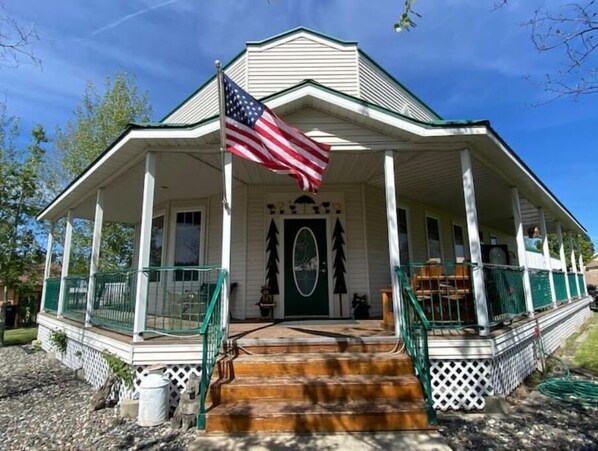 A two-story building with a porch, a flag, and a green door.