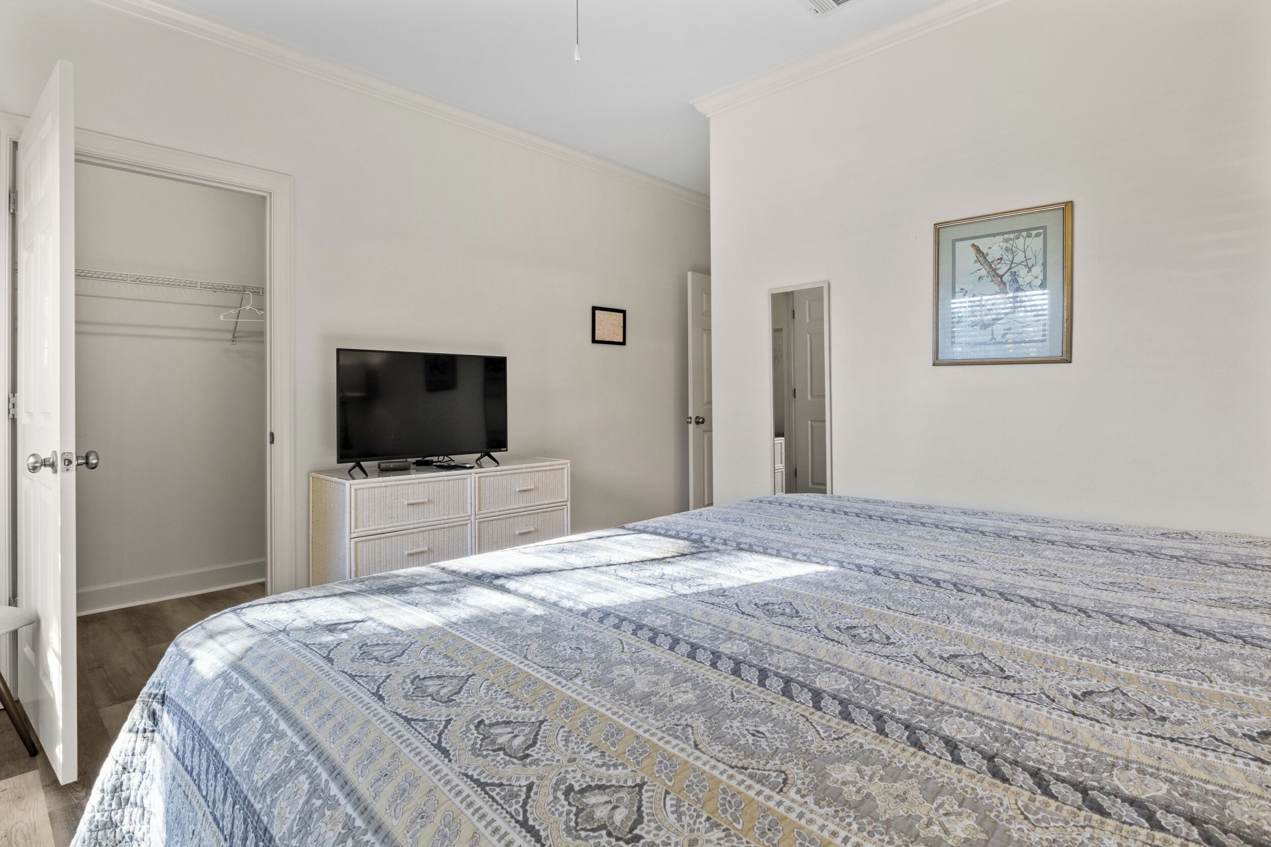 A bedroom with a large bed, a television on a dresser, and a closet with a hanging rod.