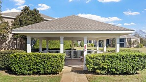 A covered outdoor area with a concrete pathway leading to a bench, surrounded by well-maintained hedges. - Ball fields! OWA! & Near the Beach! (Foley)