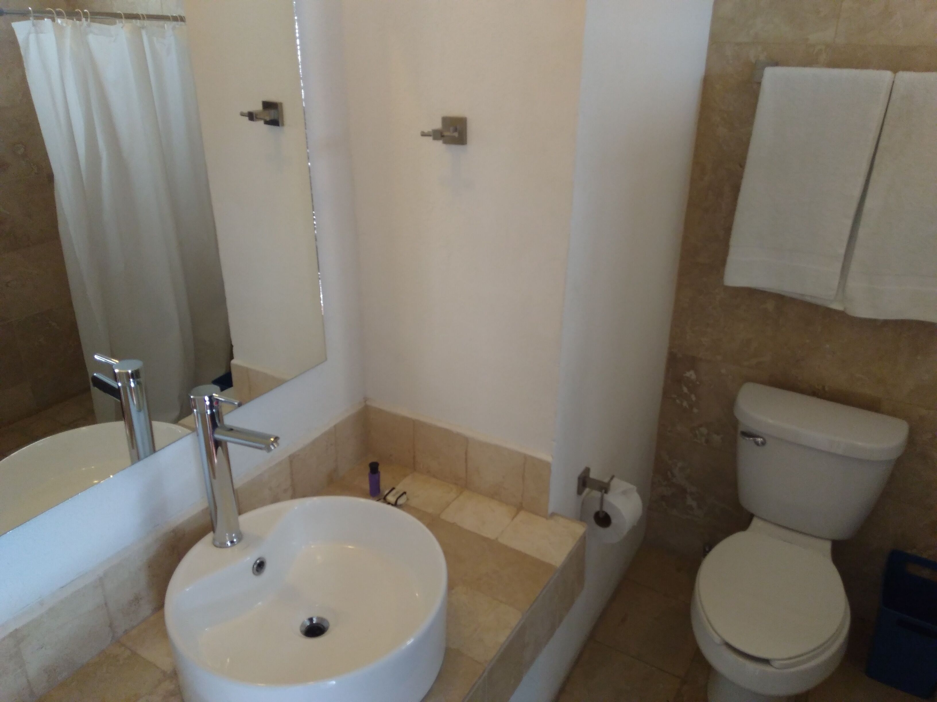 A bathroom with a sink, mirror, toilet, and shower curtain.