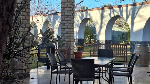 An outdoor patio with stone columns, arched ceilings, and outdoor furniture. - Casa Maru Hotel (Parras)