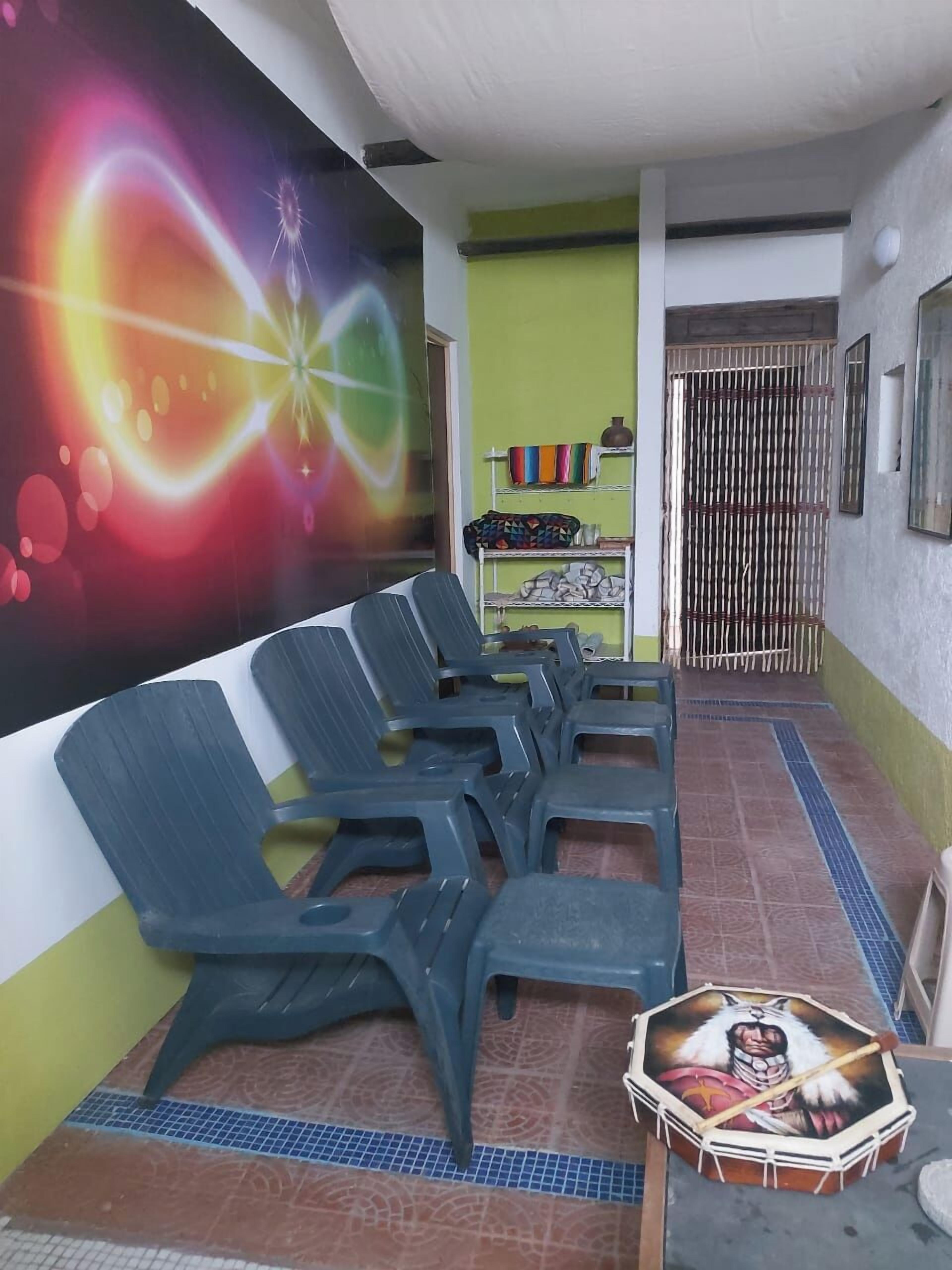 A waiting area with plastic chairs, a colorful mural, and a tiled floor.