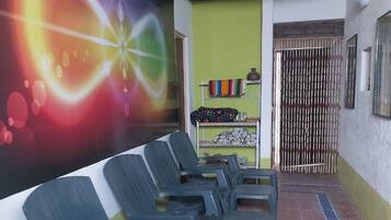 A waiting area with plastic chairs, a colorful mural, and a tiled floor.