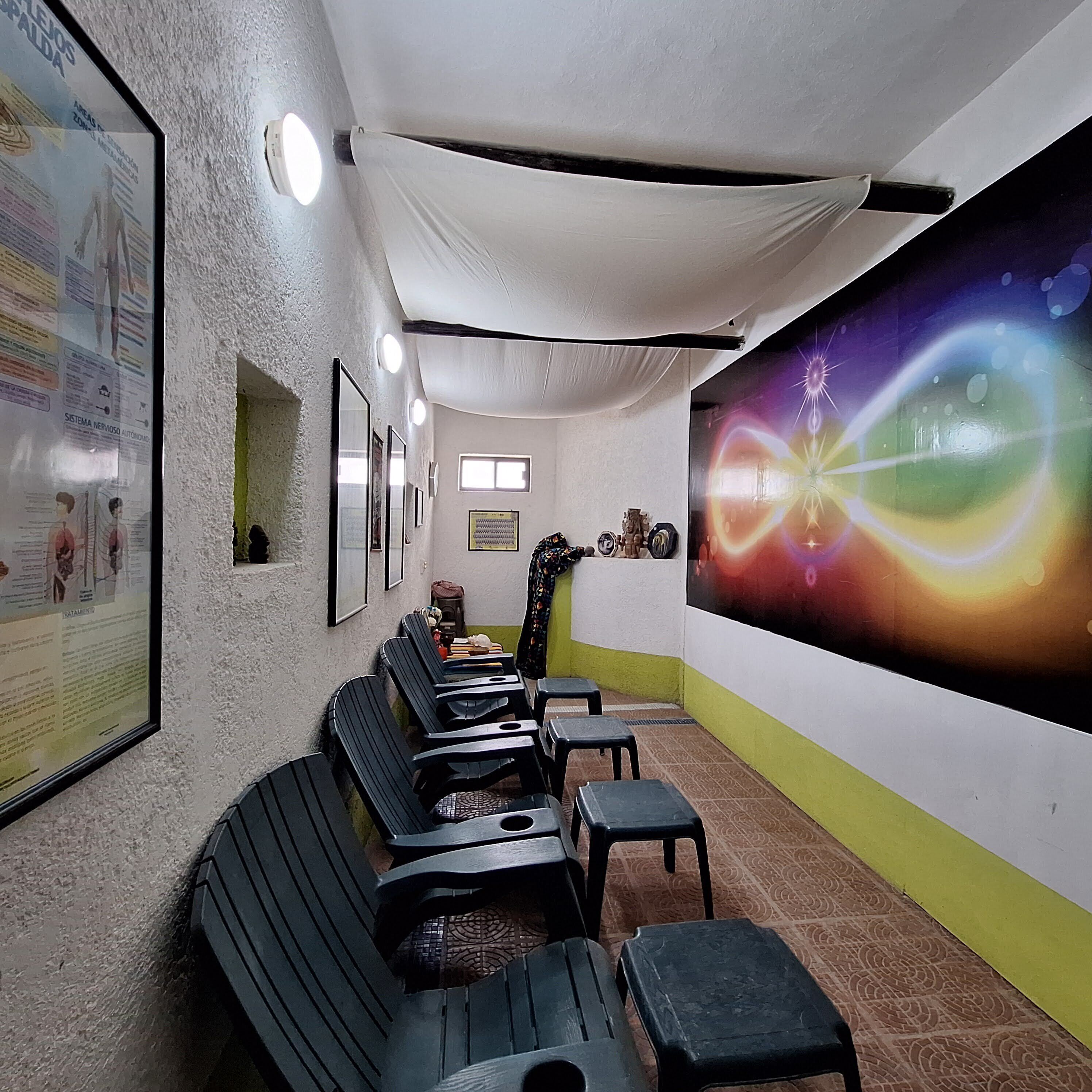 A room with black benches, a large poster on the wall, and a ceiling with a white drape.