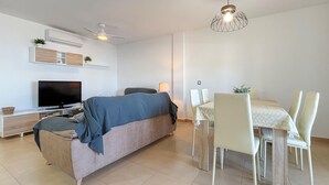 A modern living room with a sofa, TV, dining table with chairs, and a ceiling fan. - 2 bedroom amazing home in Cartagena (Cartagena)