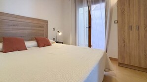 A neatly made bed with two pillows, a wooden headboard, a bedside lamp, and a wardrobe. - 2 bedroom amazing home in Cartagena (Cartagena)