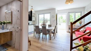Une cuisine moderne dotée d’un four encastré, un coin repas avec une table et des chaises, et un escalier menant à un canapé rouge.