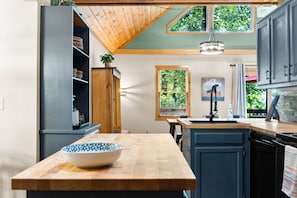 Una cocina con isla de madera, horno empotrado y ventana con vistas a la vegetación.