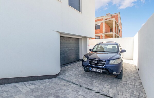 A modern building with a car parked in a narrow driveway. - Nice apartment in Vrsi with swimming pool (Vrsi)