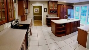 A kitchen with wooden cabinets, a white countertop, and a tiled floor.
