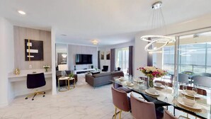 A modern living room with a sofa, TV, and dining area with a glass table and chairs. - Hidden Gem Jiminy Cricket (Kissimmee)