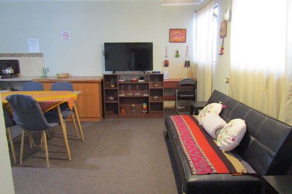 A living room with a sofa, a television, a dining table with chairs, and a kitchen area. - Casa Sutar 1 y 2 (San Pedro de Atacama)