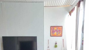 Ein Wohnzimmer mit einer Couch, Fernseher, Regalen mit Dekoration und einem Wandbild.