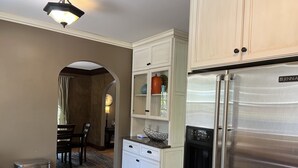 A kitchen with white cabinetry, a stainless steel refrigerator, and a built-in dishwasher. - Historic Twin Tudors Inn Southwest Room (KP1404SW) (Sioux Falls)