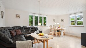 A modern living room with a leather sofa, a wooden coffee table, and a dining area with a table and chairs. - Nice apartment in Samsø with WiFi (Samsø)