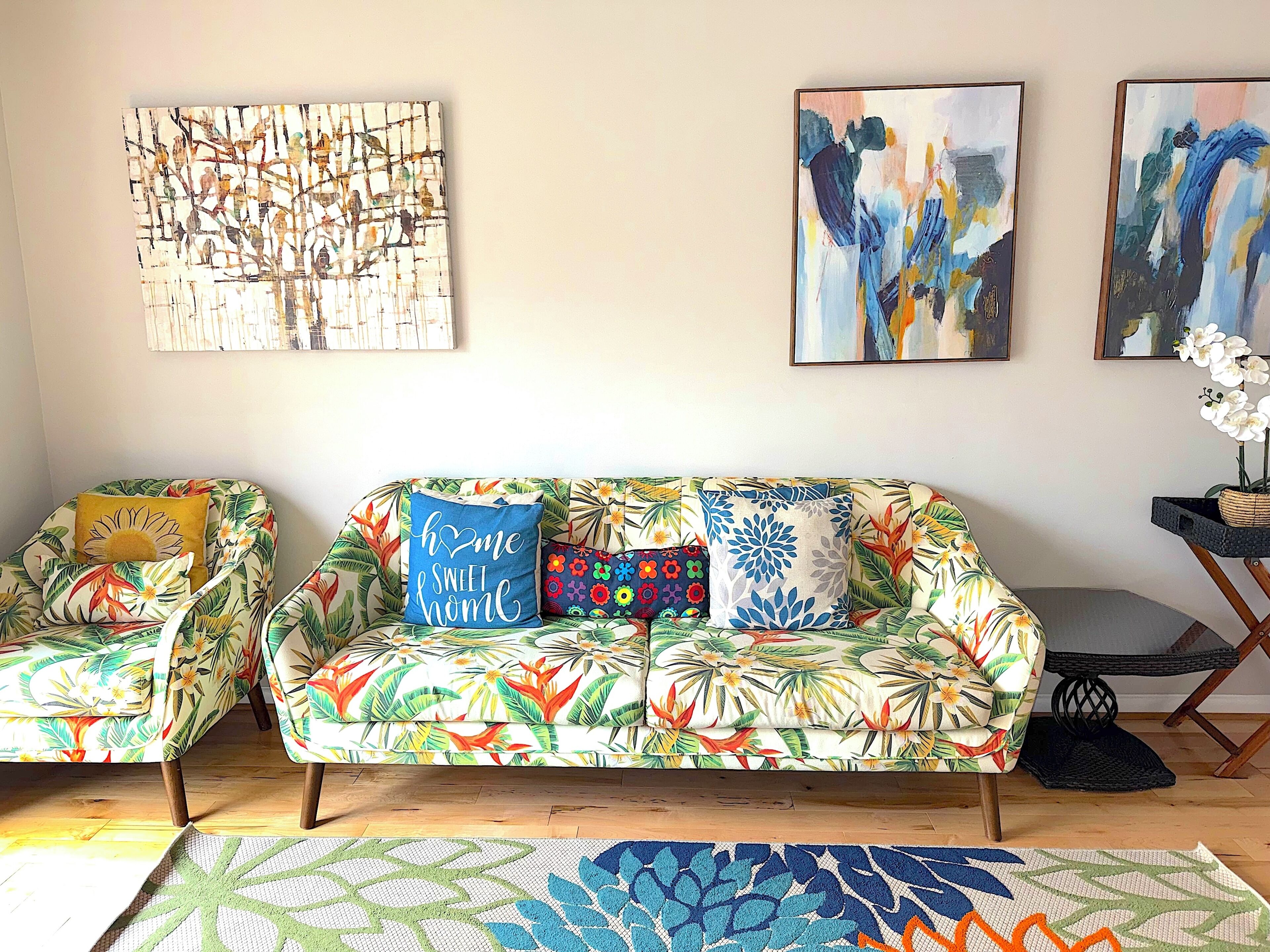 Sala de estar com sofá estampado, mesa de centro e obras de arte na parede.