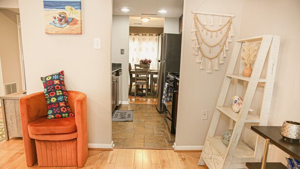 A compact living space with a kitchen, dining area, and a small seating area with a colorful cushion.