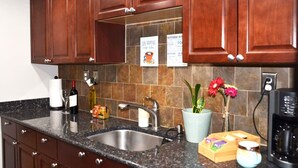 A kitchen with dark wooden cabinets, a granite countertop, a stainless steel sink, and a coffee maker.