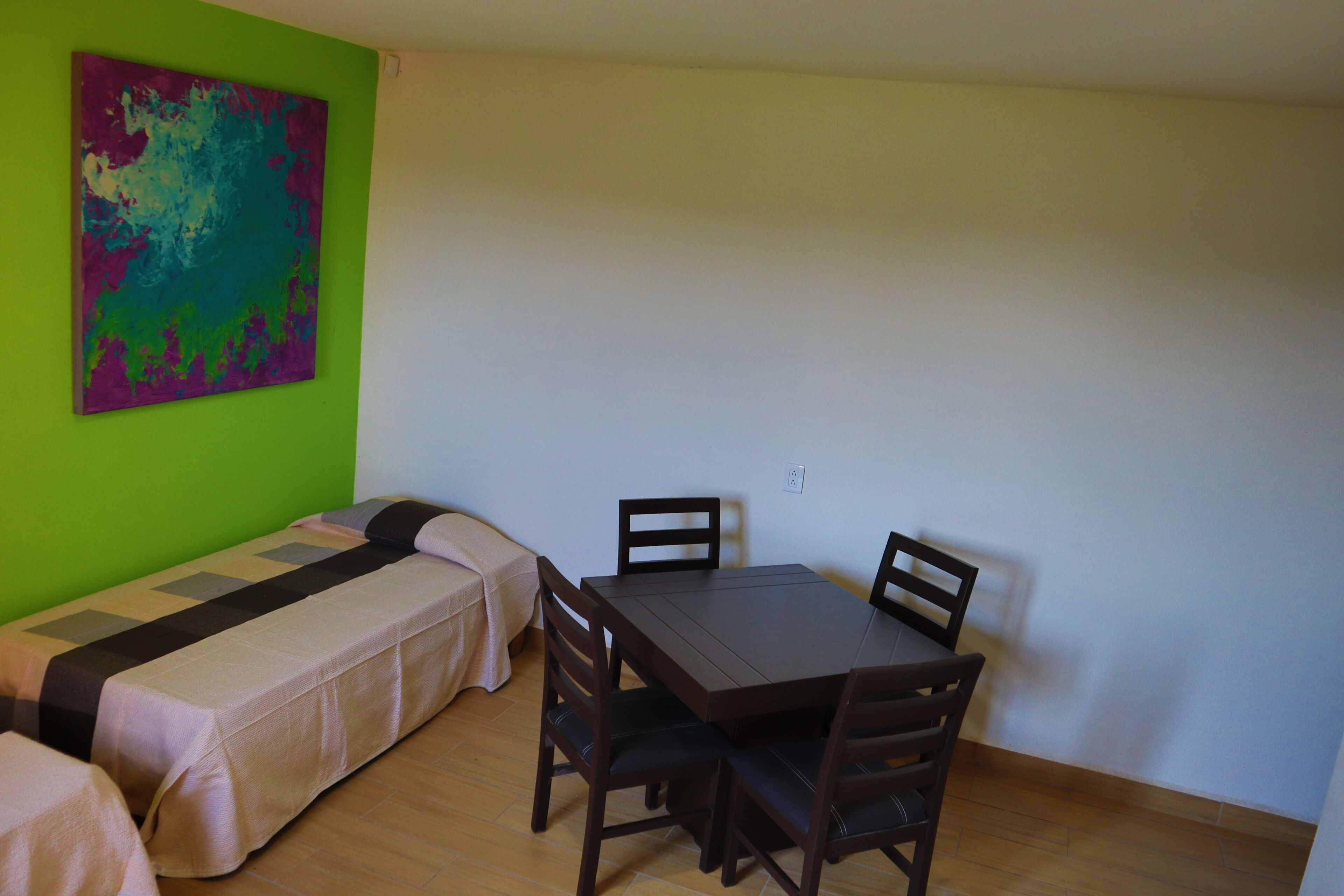 Una habitación pequeña con una cama, una mesa y dos sillas.