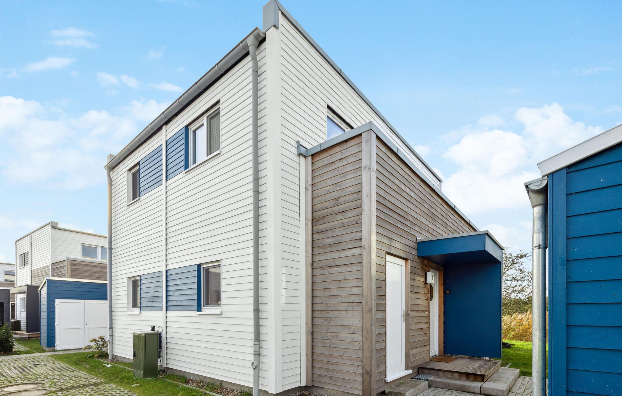 Et moderne hus i to etager med skråt tag, lille veranda og synlig garageport.